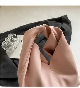 Detail of soft pink leather handbag featuring a stylish knotted handle design
