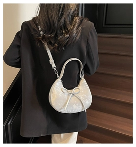Détail du sac croissant argenté avec nœud décoratif et texture métallique brillante