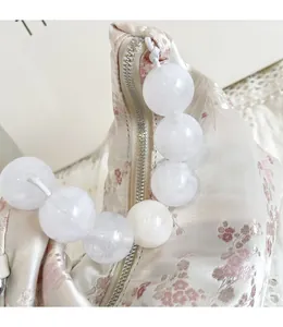 Detail of floral embroidery fabric and large translucent pearl handle on the handbag