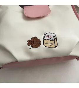 Gros plan sur la broderie ours et le cuir crème sur un sac cabas rose contrasté chic
