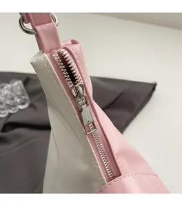Gros plan sur la fermeture éclair en métal argenté d'un cabas en cuir rose et blanc