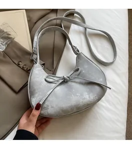 Gros plan du sac croissant argenté avec un nœud délicat et une texture en cuir grainé