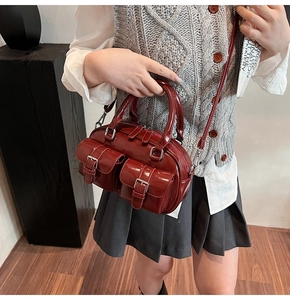 Détail du sac Boston en cuir verni rouge foncé avec finition brillante et poches avant