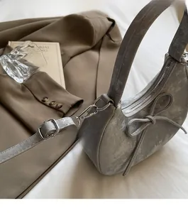 Vue détaillée du sac croissant gris nacré avec nœud et accessoires en argent