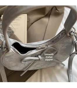 Détail d'une fermeture éclair argentée sur un sac demi-lune vintage à nœud doux