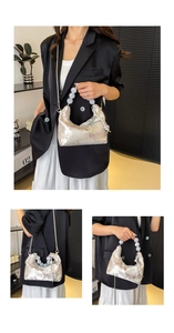 Detail of floral satin dumpling bag featuring beaded handle and metal chain strap
