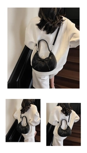 Détail d'un sac demi-lune noir avec nœud papillon, porté comme un sac baguette élégant