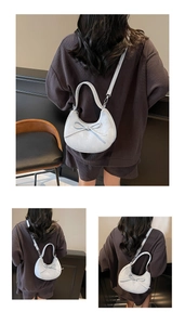 Détail du sac croissant bleu clair avec nœud décoratif et texture marbrée sur le cuir