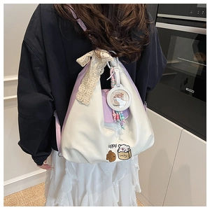 Détail du sac cabas bicolore avec un nœud en dentelle et un pendentif capybara