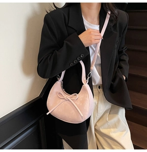 Sac demi-lune rose avec nœud décoratif porté par un mannequin pour un look stylé