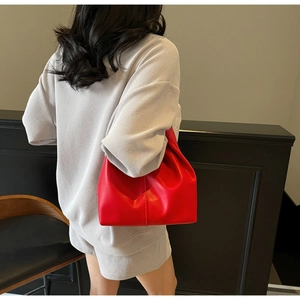 Close-up of bright red pleated leather hobo bag styled with a grey knit outfit