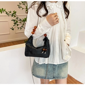 Detail of black satin handbag featuring floral embroidery and amber beaded top handle