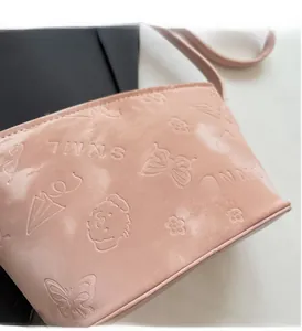 Détail de motifs papillons et fleurs gaufrés sur le sac seau en cuir rose pâle