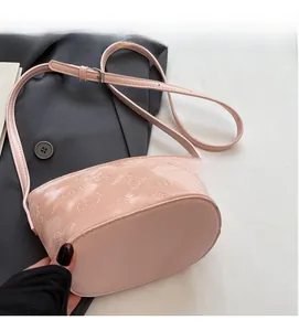 Détail du sac seau en cuir verni rose avec papillons et ours gaufrés en relief
