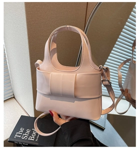 Détail du sac à main rose pâle verni avec grand nœud et bandoulière réglable