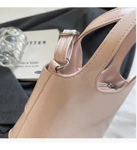 Détail du sac à main en cuir verni rose brillant avec anneau en D en métal argenté poli
