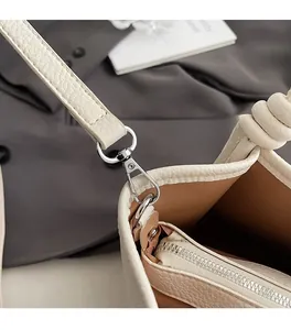 Detailed close-up of cream leather bucket bag with silver metal lobster clasp and hardware