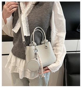 Close-up of light gray pebble leather bucket bag with knotted handle and round pouch