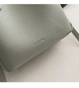Detailed close-up of sage green lychee textured leather with embossed logo on bucket bag