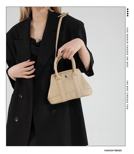 Beige bucket bag with lychee grain leather and silver buckle on a black suit