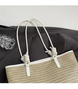 Detail of thin leather shoulder straps and beige woven texture on the tote bag