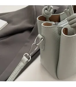 Close-up of light green lychee pattern leather and silver metal hook on bucket bag
