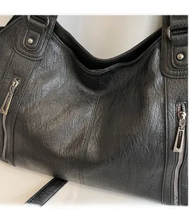 Close-up of black leather tote bag showing soft textured fabric and silver zipper detail