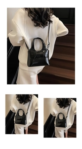 Détail d'un sac à main en cuir verni noir avec un grand nœud et une fine bandoulière