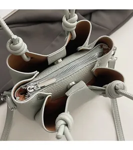 Top-down view showing smooth silver zipper and magnetic snap closure on green bucket bag