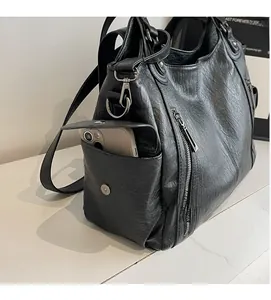 Detail view of black leather dumpling bag side pocket showing smartphone capacity