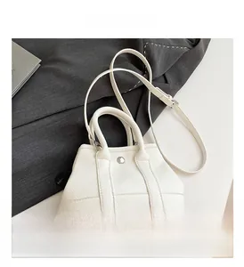 Detailed view of white bucket bag with pebble leather texture and metal ring handles