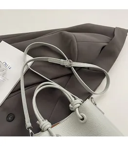 Detail of mint green bucket bag featuring lychee grain leather and knotted handle design