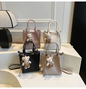Detail view of colorful bucket bags in lychee leather with cute bear charms