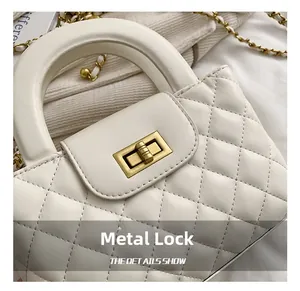 Detailed close-up of white quilted leather handbag featuring a golden turn-lock clasp