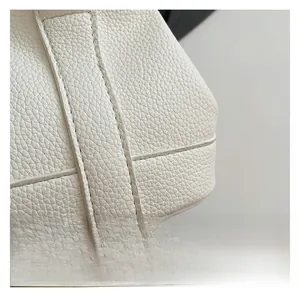 Close-up detail of white lychee-pattern leather with precise stitching on a bucket bag