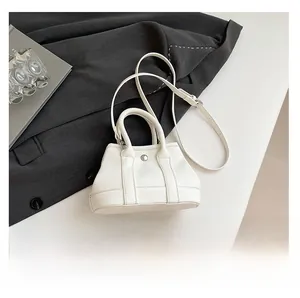 Detailed close-up of white lychee pattern bucket bag with metal buckle and shoulder strap