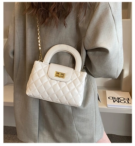 Detail of white quilted leather handbag featuring a golden clasp and metal chain strap