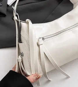Detalle de bolso de cuero PU blanco crema con cremalleras plateadas y borlas flecos