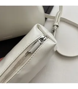 Detail of a smooth silver zipper on a white faux leather bucket bag with neat stitching