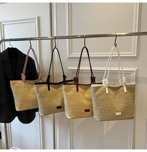 Detail of straw tote bags in four colors with knot straps and woven texture hanging on rack