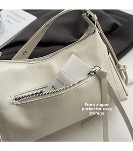 Detalle de bolso de hombro en ecocuero beige con práctico bolsillo frontal con cremallera plata