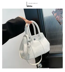 Close-up of white pebble leather bucket bag featuring silver turn-lock and handle detail