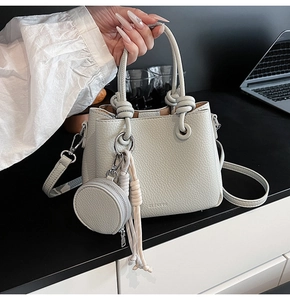 Detail of lychee pattern leather bucket bag with knotted handle and round coin purse