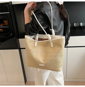 Detail of hand-woven straw tote with elegant knot handle and white leather trim