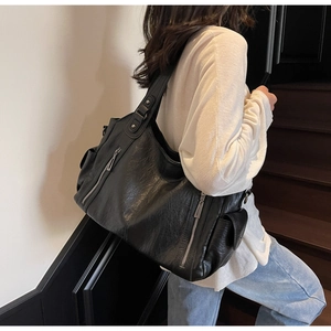 Close-up of black retro tote bag with side zipper pockets and soft leather texture