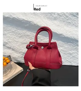 Detail of red pebbled leather bucket bag with silver hardware and detachable strap
