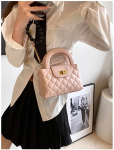 Detail of pink quilted crossbody bag with golden turn-lock and black beaded chain charm