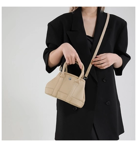Detail of lychee pattern leather bucket bag with silver metal buckle on a black blazer
