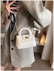 Detail of white quilted crossbody bag with gold twist lock and beaded chain strap