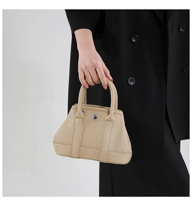 Detailed close-up of beige lychee grain leather bucket bag with silver snap button